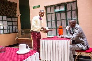 Dois homens estão numa mesa com uma toalha de mesa. em Hummingcage em Nairobi