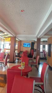 ナイロビにあるHummingcageの赤い椅子とテーブル、スクリーンが備わる待合室