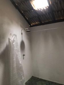 a shower in a room with a white wall at Hostel Nugeku in Rincón