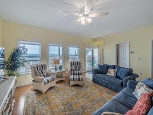 een woonkamer met een blauwe bank en stoelen bij Ocean Splendor in Surf City