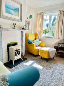 a living room with a yellow chair and a fireplace at Unique Cosy Cottage In Sherwood Forest in Edwinstowe
