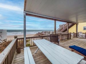 een houten terras met een bank en het strand bij Ocean Splendor in Surf City