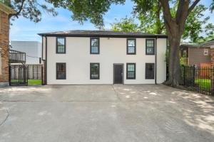 una casa blanca con un árbol en la entrada en The King's Retreat I, en Houston