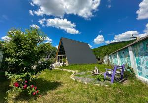 蓋貝萊的住宿－Qafqaz Mountain Chalet，一个带紫色长椅和大楼的花园