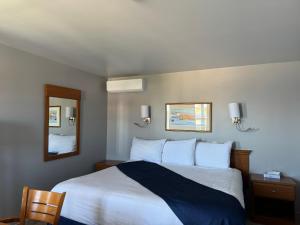 1 dormitorio con 1 cama grande y espejo en Hotel-Motel Fleur de Lys en Perce