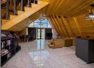 Qafqaz Mountain Chalet في غابالا: غرفة معيشة كبيرة بسقف خشبي ودرج