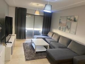 ein Wohnzimmer mit einem Sofa und einem Tisch in der Unterkunft Marina Saidia Luxury Apartment with pool & Garden view. Residence Tamaris in Saidia 