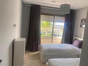 1 Schlafzimmer mit 2 Betten und einem Fenster in der Unterkunft Marina Saidia Luxury Apartment with pool & Garden view. Residence Tamaris in Saidia 