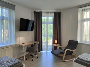 een kamer met een bureau, 2 stoelen en een televisie bij Business apartments "An der Lutherkirche" Self-Check-in in Weißenfels