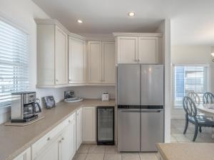 a kitchen with white cabinets and a stainless steel refrigerator at Over The Moon in Kure Beach