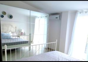 a white bedroom with a mirror and a bed at Casa Dama in Vietri sul Mare
