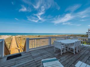 a deck with a table and chairs and the beach at Over The Moon in Kure Beach
