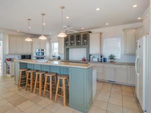 a kitchen with white cabinets and a blue island with bar stools at Over The Moon in Kure Beach