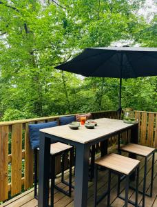una mesa y sillas con una sombrilla en la cubierta en Barbuy - Natuurhuisje in Durbuy - Bar - Zwem - Ontspan, en Durbuy