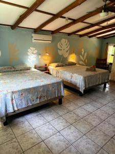 a bedroom with two beds and a wall with flowers at Hotel Entre Dos Aguas in Sámara