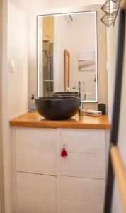 ein Waschbecken im Bad mit einer schwarzen Schüssel auf einer Holztheke in der Unterkunft La Maison du Cotton- Gite bio-climatique in Andernos-les-Bains
