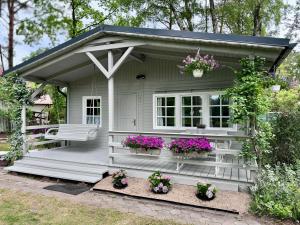 Un pequeño cobertizo blanco con flores y un banco. en Zacisze u Ani, en Dębki