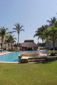 a swimming pool with palm trees and a building at Departamento en zona diamante Acapulco in Acapulco