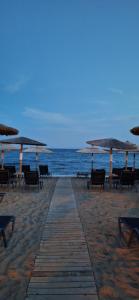 una spiaggia sabbiosa con ombrelloni, sedie e l'oceano di Dimis Home a Nea Plagia