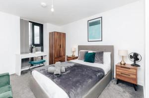 ein Schlafzimmer mit einem großen Bett und einem grünen Stuhl in der Unterkunft Luxury 2 Bedroom Apartment, Broad street Birmingham in Birmingham