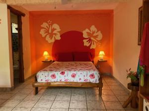 a bedroom with a bed with an orange wall at Hotel Entre Dos Aguas in Sámara