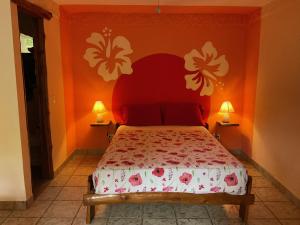 a bedroom with a bed with an orange wall at Hotel Entre Dos Aguas in Sámara