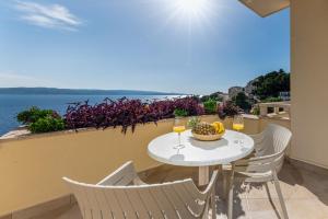 a table and chairs with wine glasses on a balcony at Apartments Kartulina in Brela