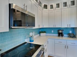 a kitchen with white cabinets and blue tiles at Pelican Landing in North Topsail Beach