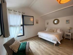 a white bedroom with a bed and a window at Gîte Cala Verde Jardin, à 4km de la première plage in Audenge