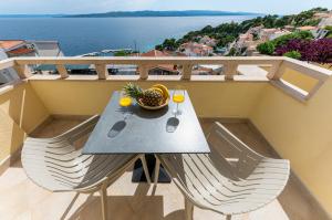 a table with two glasses and a bowl of fruit on a balcony at Apartments Kartulina in Brela