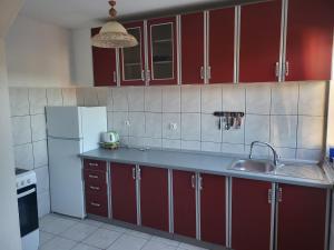 a kitchen with red cabinets and a sink and a refrigerator at Villa Harmony in Bihać