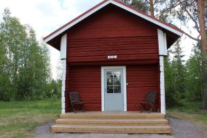 a red cabin with two chairs in front of it at Suomela Camping in Kärsämäki