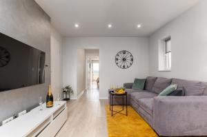 a living room with a couch and a clock on the wall at Apartments Kartulina in Brela