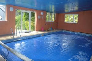 a large swimming pool with blue water in a room at Miller's Cottage in Woolfardisworthy