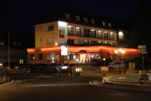 a building with red lights on a street at night at Bagnoles Hotel - Contact Hotel in Bagnoles de l'Orne