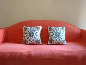 - deux oreillers installés sur un canapé rouge dans l'établissement L'Orto di Sant'Andrea, à Pise