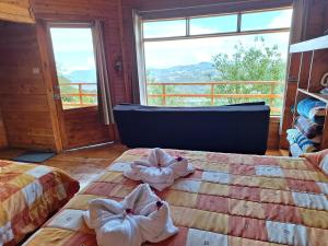 two beds in a room with a large window at Hotel Mirador de Quetzales in Providencia
