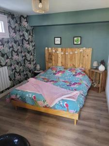 a bed with a wooden headboard in a bedroom at La jolie Parenthèse in Longevilles-Mont-dʼOr +1 photo