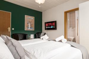 a bedroom with a large white bed with a green wall at Elbling Appartement for 4 People - Billiards - 2 Bedrooms - 2 Bathrooms - Balcony with Mosel View - Parking - Wine Barrel Bar - Fully Equipped Kitchen - Netflix - WaipuTV - 3 km from Cochem in Klotten