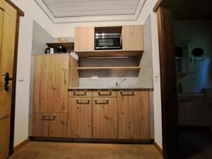 a kitchen with wooden cabinets and a microwave at Bauernhaus 128 Stube 2 Oberkirchleitn by S4y in Sankt Oswald