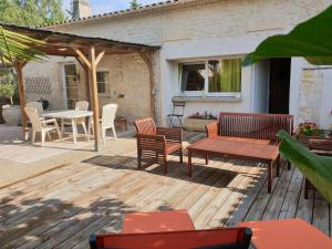 a deck with benches and a table and chairs at Maison de charme à Meursac avec piscine in Meursac