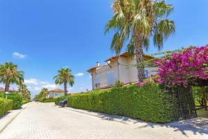 Una casa con flores moradas y palmeras en una acera. en Paradise Town Villa Hazel, en Belek