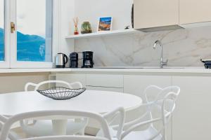 a white kitchen with a white table and chairs at Benaco Hause 3 in Brenzone sul Garda