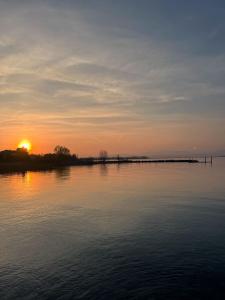 una puesta de sol sobre una gran masa de agua en Prima Luce, en Peschiera del Garda