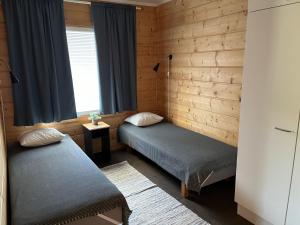 Duas camas num quarto com paredes de madeira e uma janela em Taljatie Apartments em Rovaniemi