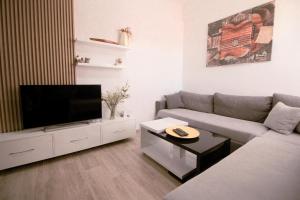 a living room with a couch and a flat screen tv at Arber's Home in Sarandë