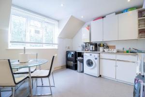 cocina con mesa, lavadora y secadora en Comfy private room in Battersea close to Clapham Junction, en Londres