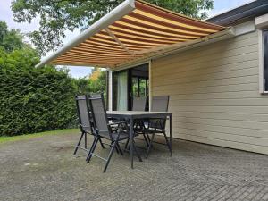 een patio met een tafel en stoelen onder een pergola bij Modern Chalet in Garderen with Private Garden in Garderen