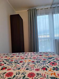 sypialnia z łóżkiem z kwiatową narzutą i oknem w obiekcie Turkusowa Apartament w Szczecinie