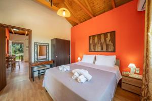 a bedroom with orange walls and a bed with towels at Moudilos 1 in Lixouri